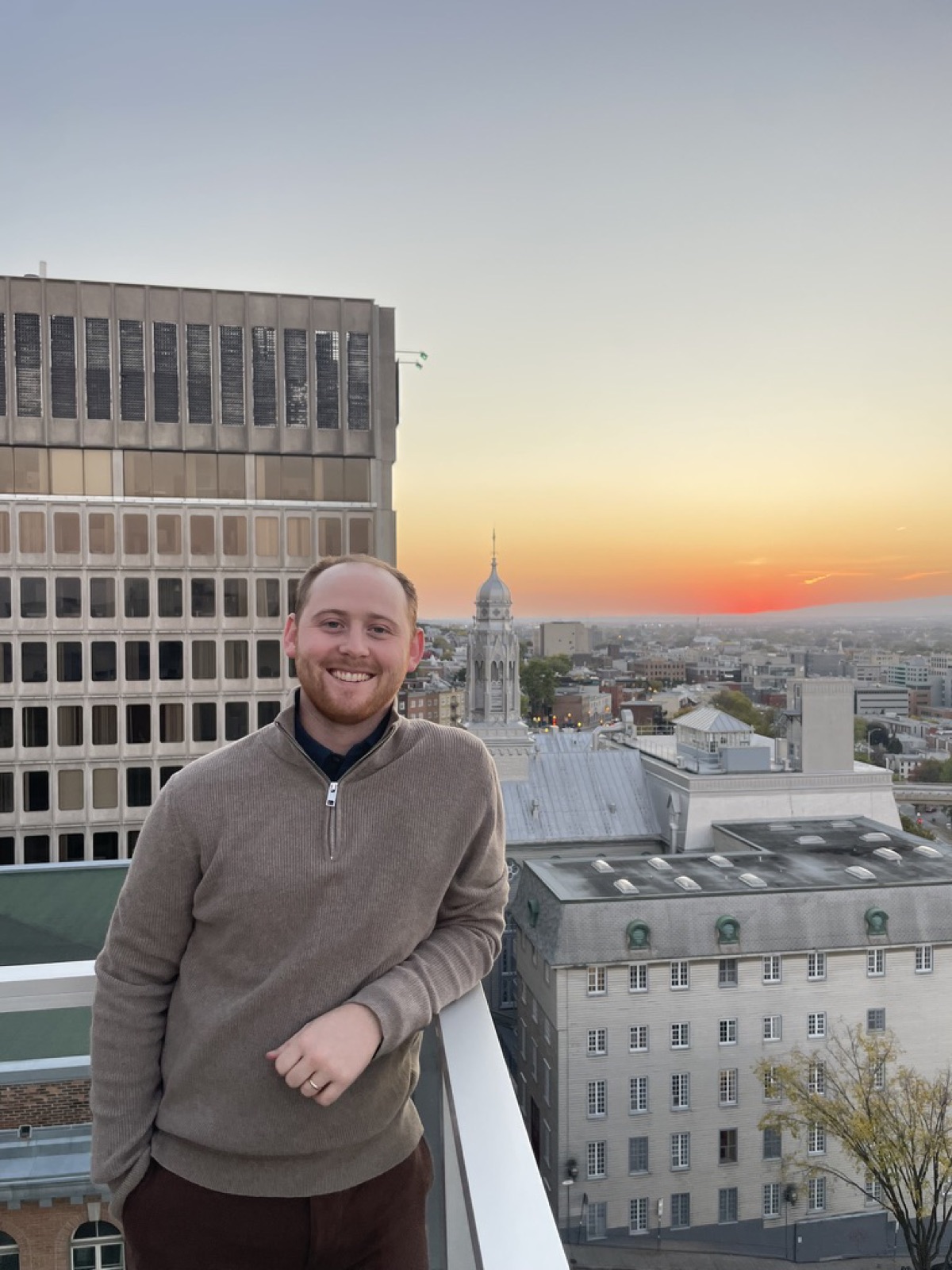 Noah Remmert smiling on a rooftop at sunset